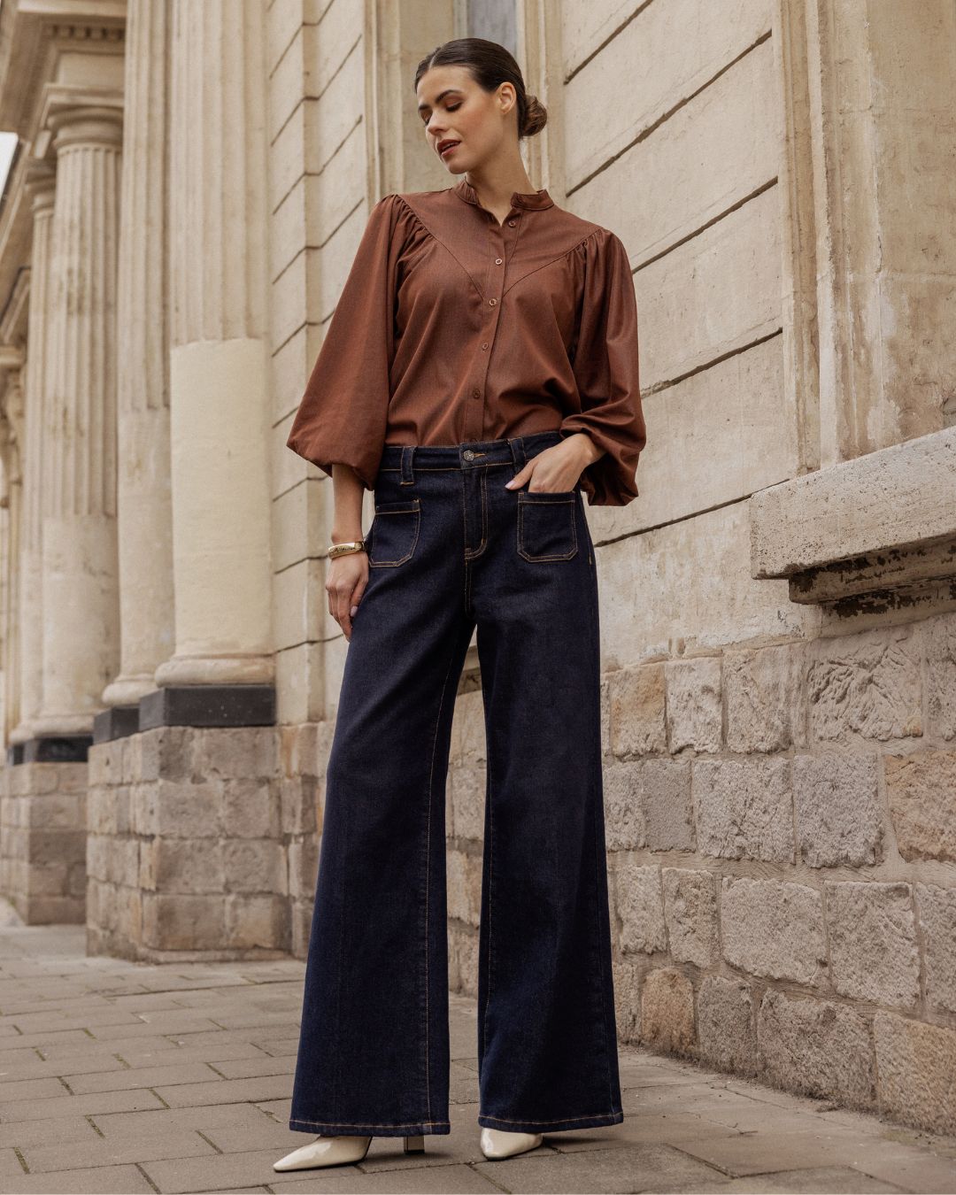 Vrouw in een donkerblauwe wide leg jeans en bruine blouse van Florèz